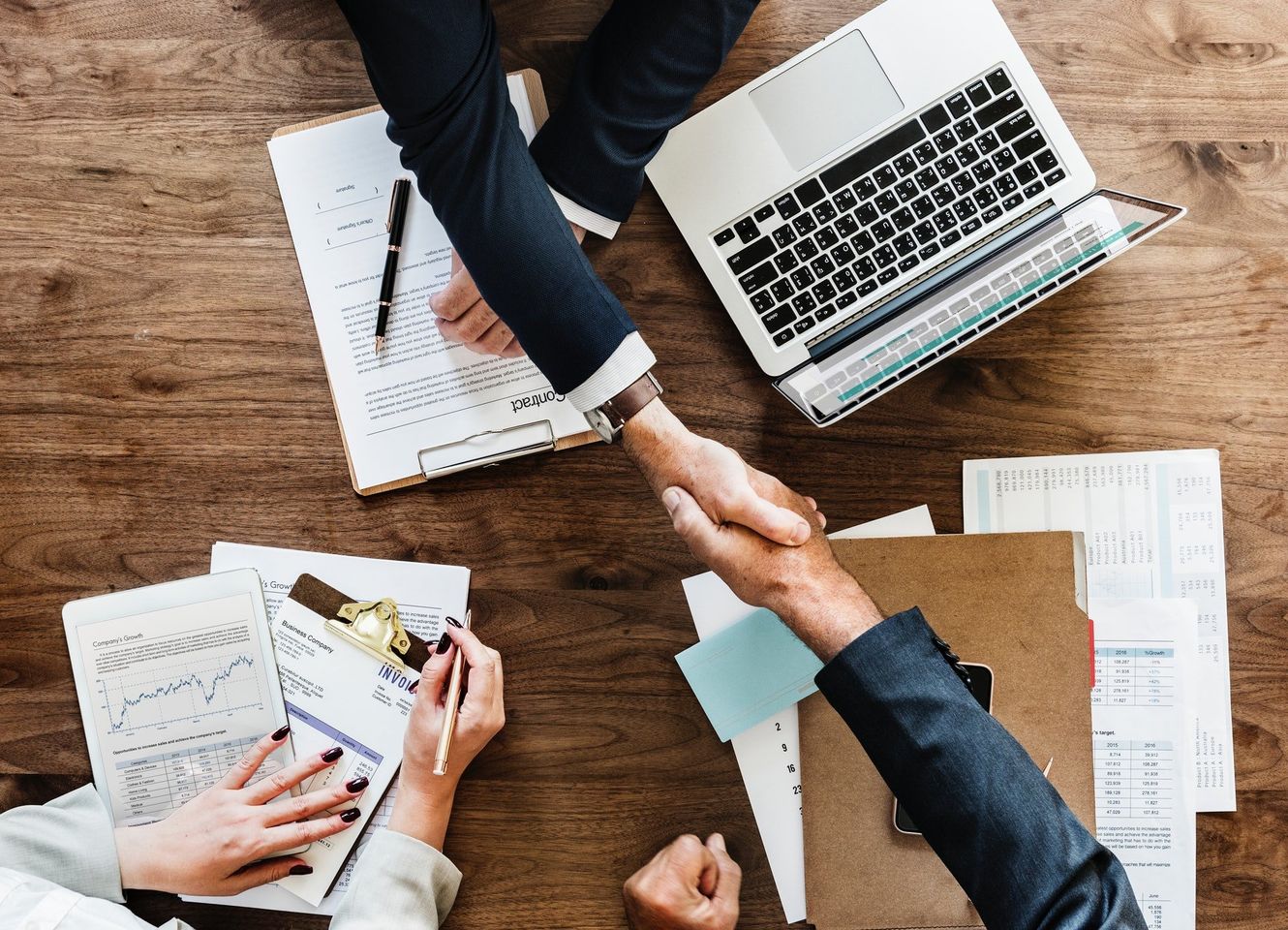 Acuerdo de negocios junto a documentos y una computadora